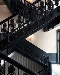 A grand black iron staircase with ornate railings and lighting in an interior setting.