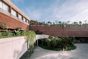 Modern building exterior featuring brick and concrete materials with greenery.