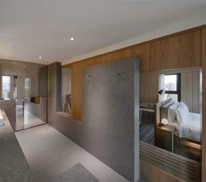 Modern hotel room with concrete walls and floor, minimalist design, and sliding glass doors.
