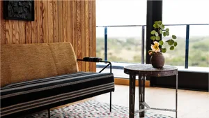 A modern interior with a wooden floor, featuring a sofa and a side table with a vase and flowers.
