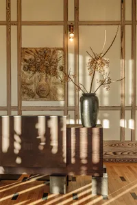 Modern living room with wooden paneling, a vase with dried flowers, and a painting of a vase with dried flowers.