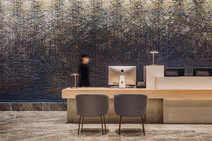 A modern reception desk featuring a metal cable net design with marble flooring and a blurred figure in the background.