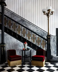 A modern staircase with red upholstered chairs and a marble railing.