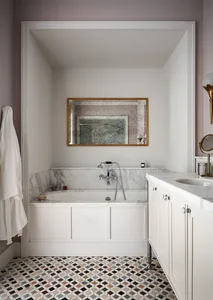 A minimalist bathroom featuring marble walls and a mosaic tile floor.