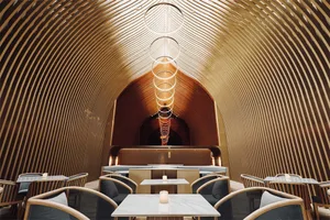 A modern restaurant interior featuring wooden elements and circular light fixtures.
