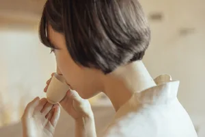 Person drinking from a ceramic cup