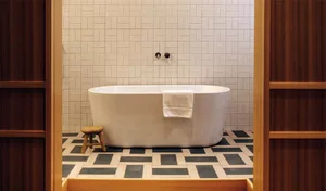 Modern bathroom featuring a sleek white freestanding tub with a white towel draped over the side, set against a background of