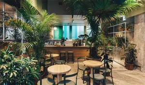 A modern cafe interior with wooden tables and green plants.