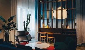 Modern living room featuring glass windows, dark wood furniture, and greenery.