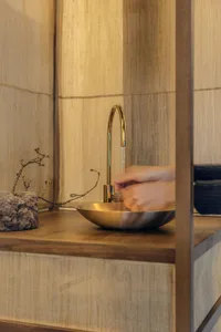 雙手在簡約廚房的金屬水槽與木質檯面上清洗。