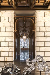 Modern lobby featuring a grand marble entranceway with multiple archways and illuminated hanging lamps.