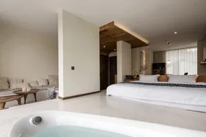 A minimalist bedroom with a white bed, wooden accents, and a bathtub.