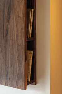 Modern wooden cabinet with books on a wall-mounted shelf.
