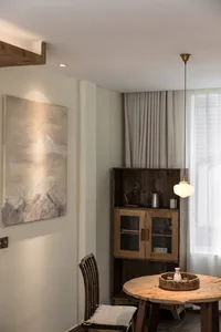A modern dining room featuring a wooden table and chair, with a wooden cabinet and window with curtains.