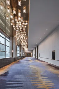 Long corridor with industrial design featuring marble walls and concrete floors, illuminated by modern lighting fixtures.