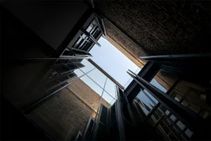 Steel-glass-brick building inner space looking up towards the sky.