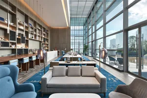 A modern hotel lobby featuring glass walls and concrete furniture.