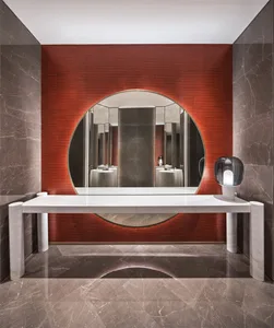 Modern bathroom with circular mirror, white marble sink, and red wall tiles.
