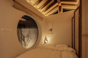 A minimalist bedroom with a wooden bed and a circular window
