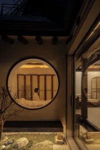 A minimalist residential interior featuring wooden and stone elements, complemented by glass