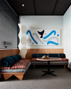 A modern cafe interior with wooden benches, fabric cushions, and a paper lantern.