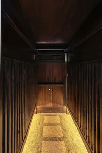 A narrow wooden corridor with textured carpet flooring and a wooden door at the end.