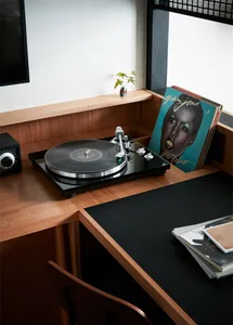 A modern home office setup featuring a wooden desk with a record player and records.