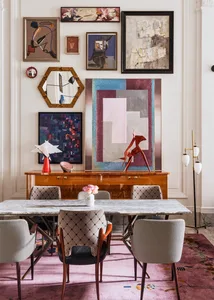 A modern dining room featuring a marble table, wooden chairs, and a vibrant art wall.