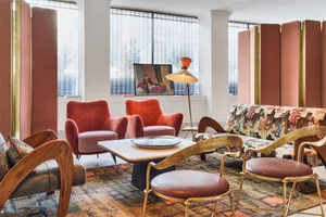 A modern interior design setup featuring red chairs, a lamp, and a patterned fabric sofa.