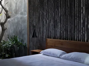 A bedroom with a metal accent wall, white bedding, and wooden headboard.