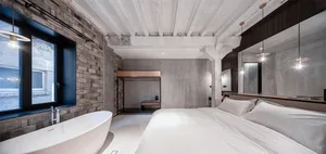 A minimalist bedroom featuring industrial materials, concrete walls, and white bedding.