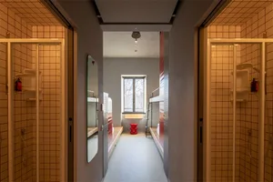 A modern, industrial-style hostel room featuring tiled walls and concrete bunk beds.