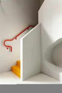 A metallic red staircase with a curved red handrail.