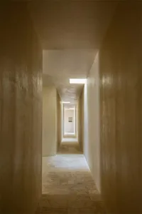 A minimalist corridor with concrete walls and a skylight.