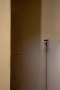 A minimalist entryway featuring a tall, slender metal candlestick with a single white candle.