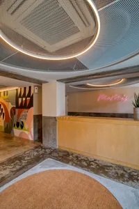A minimalist reception desk made of wood and concrete, featuring a circular light fixture above it.