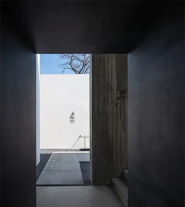 A modern entrance with concrete walls and a clear view of a blue sky through a window.