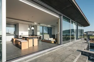 Modern living and dining room with glass walls and concrete finishes.