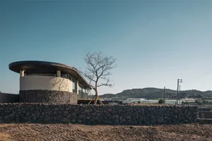 A modern residential building with a metal roof and glass walls.
