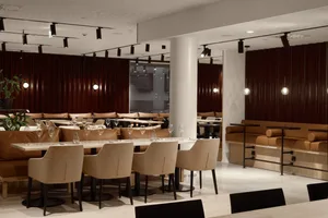 Modern restaurant interior with tables, chairs, and stylish decor made of wood, leather, and metal.