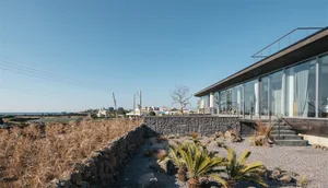 Modern vacation home featuring glass walls and stone exterior on a clear day.