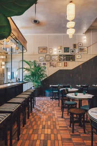The interior design of a brass bar restaurant showcases a stylish, modern space with brick tile flooring, green foliage, and 