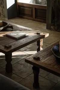 Wooden tables in an industrial-style living room with natural light and exposed stone walls.