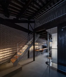 Industrial residential living space featuring brick walls, metal railings, and wooden stairs.