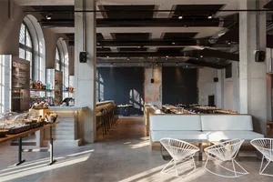 Industrial-style restaurant interior with concrete flooring, wooden benches, and metal accents.