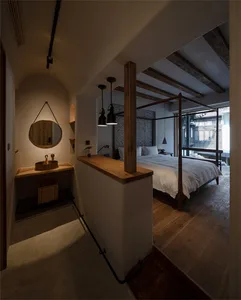 A minimalist bedroom with a white bed, wooden frame, and hanging lamps.