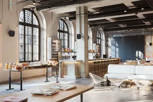 A minimalist cafe bar with concrete flooring, white furniture, and industrial-style lighting.