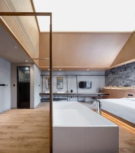 Modern bedroom featuring white furniture, minimalist design, wooden floors, concrete walls, and a brick accent wall.
