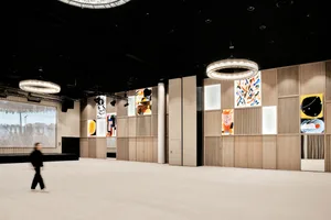 A spacious, modern conference hall with wooden paneling and glass walls.