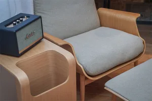 A modern, minimalist living room with an armchair made of wood and upholstered cushions, featuring a Marshall Bluetooth speak